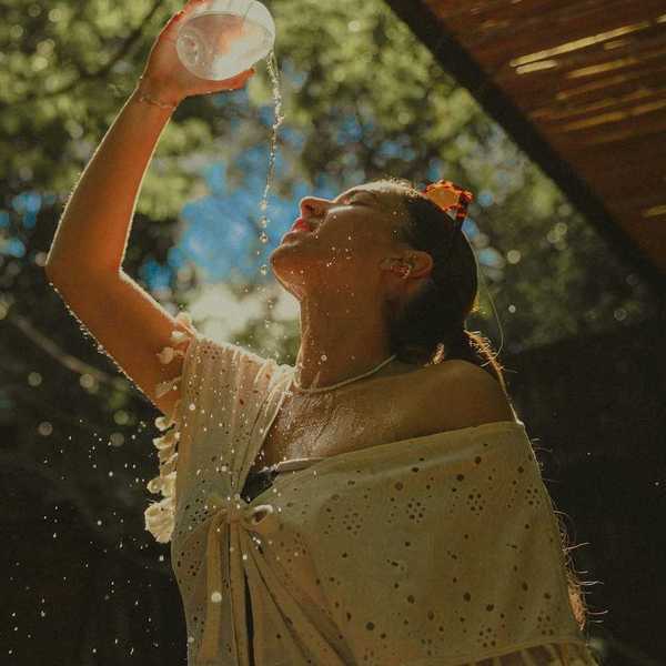 Woman in light clothing, cooling off by pouring water over herself.