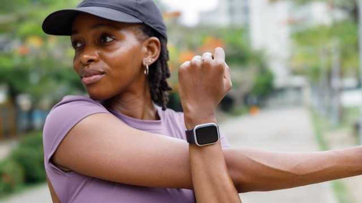 Woman in running gear stretching with a smartwatch on her wrist