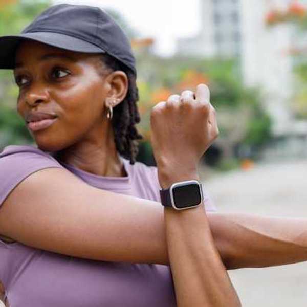 Woman in running gear stretching with a smartwatch on her wrist