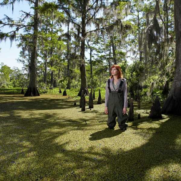Woman in waders standing shin-deep in southeastern swamp