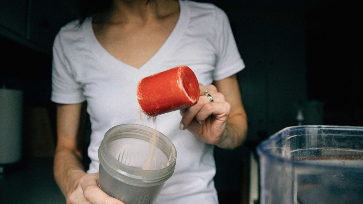 woman in white crew neck t-shirt holding red plastic cup with protein powder in it