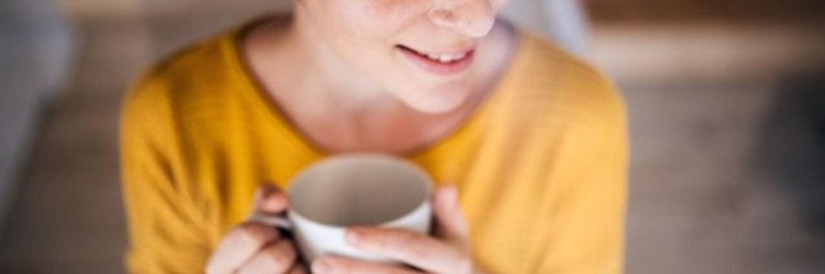 Woman in yellow sweater holding a cup of coffee.
