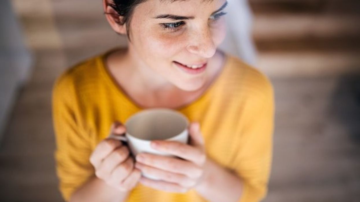 Woman in yellow sweater holding a cup of coffee.