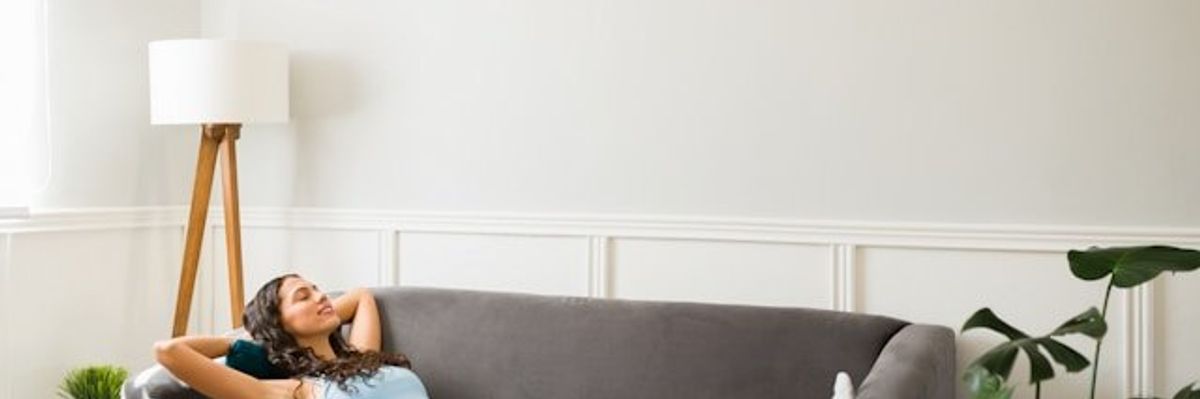 Woman lying on a sofa beneath a wall air conditioning unit