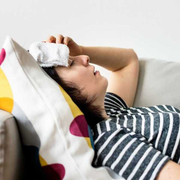 Woman, lying on a sofa with cold compress on forehead coping with extreme heat