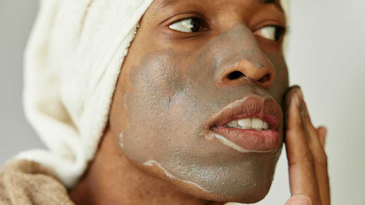 Woman of color applying cream or lotion to face