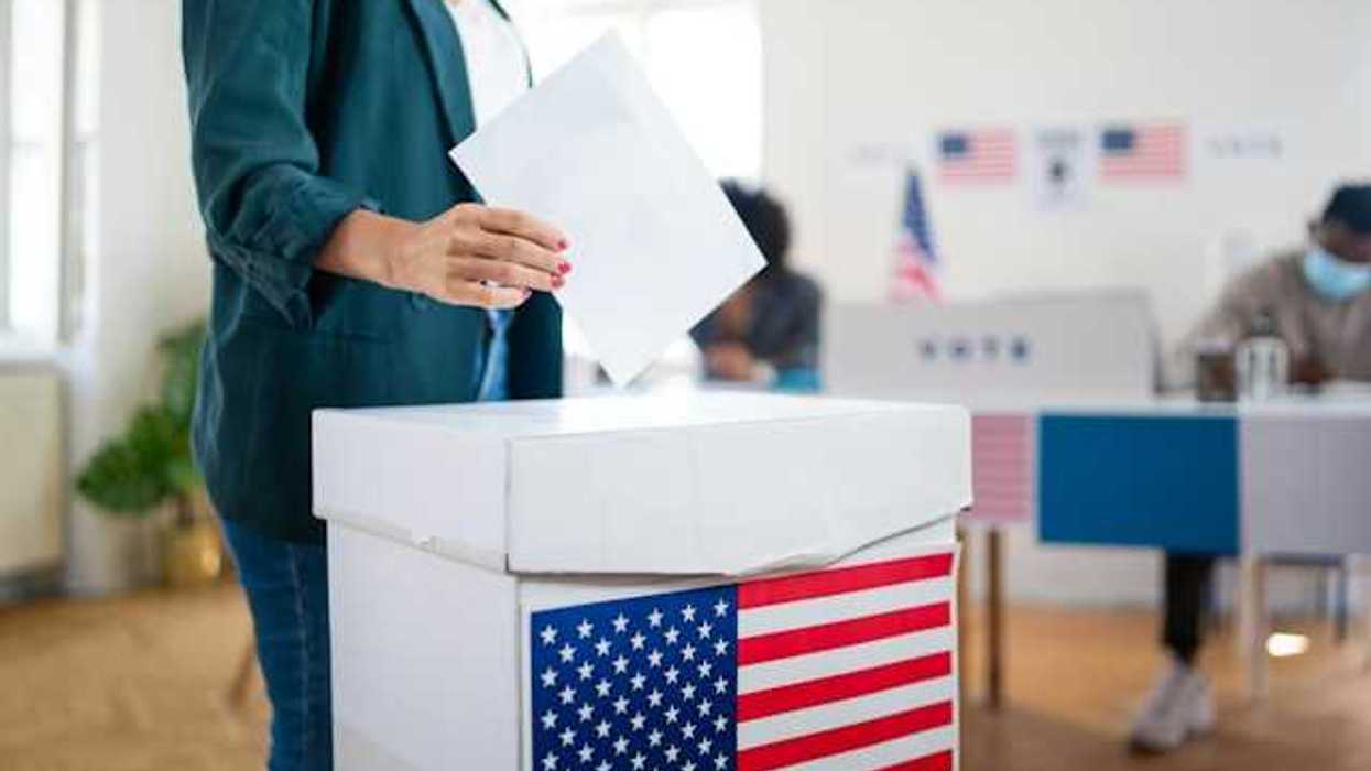 Woman placing ballot in cardboard ballot box