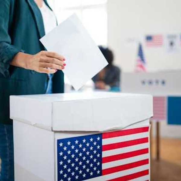 Woman placing ballot in cardboard ballot box