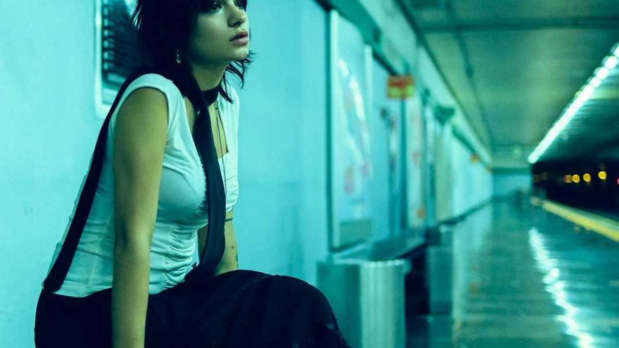 Woman seated on bench in underground station, waiting for subway for train