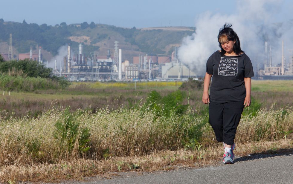 Woman walking by oil refinery