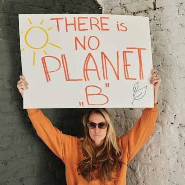 Woman wearing an orange sweatshirt holding a sign saying There is no planet B