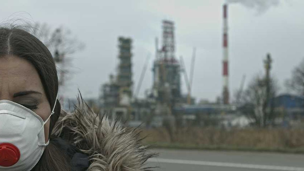 Woman wearing face mask standing in front of an industrial building