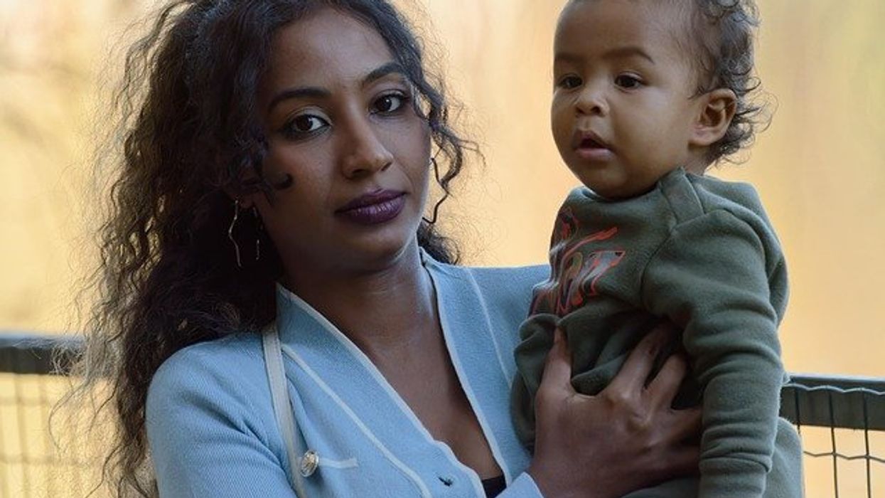 Woman with long brown hair holding a toddler.