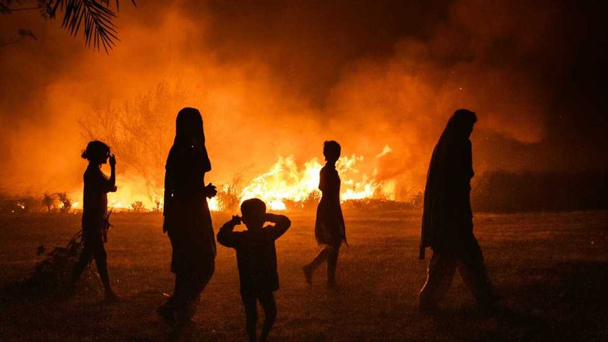 Women and children silhouetted against fire
