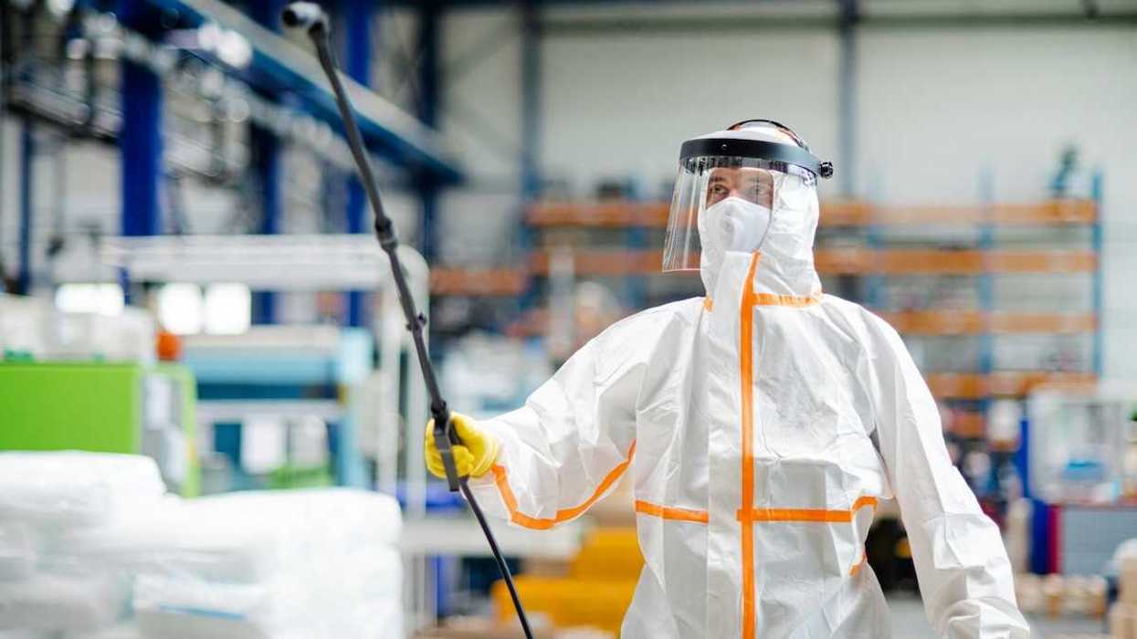 Worker in haz-mat suit spraying a room