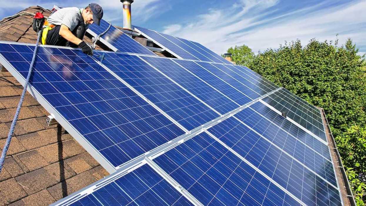 Worker installing solar panels on a shingled residential rooftop