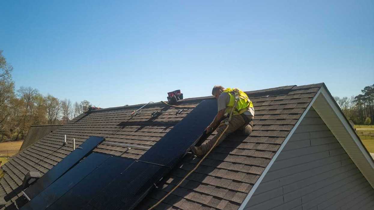 Workman installing solar panels on a residential roof