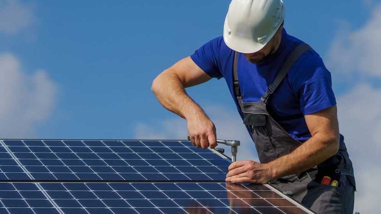 Workman securing a rooftop solar panel with a ratchet and socket wrench