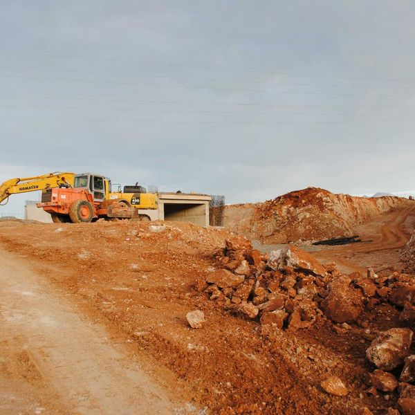 yellow excavator near brown rock formation during daytime