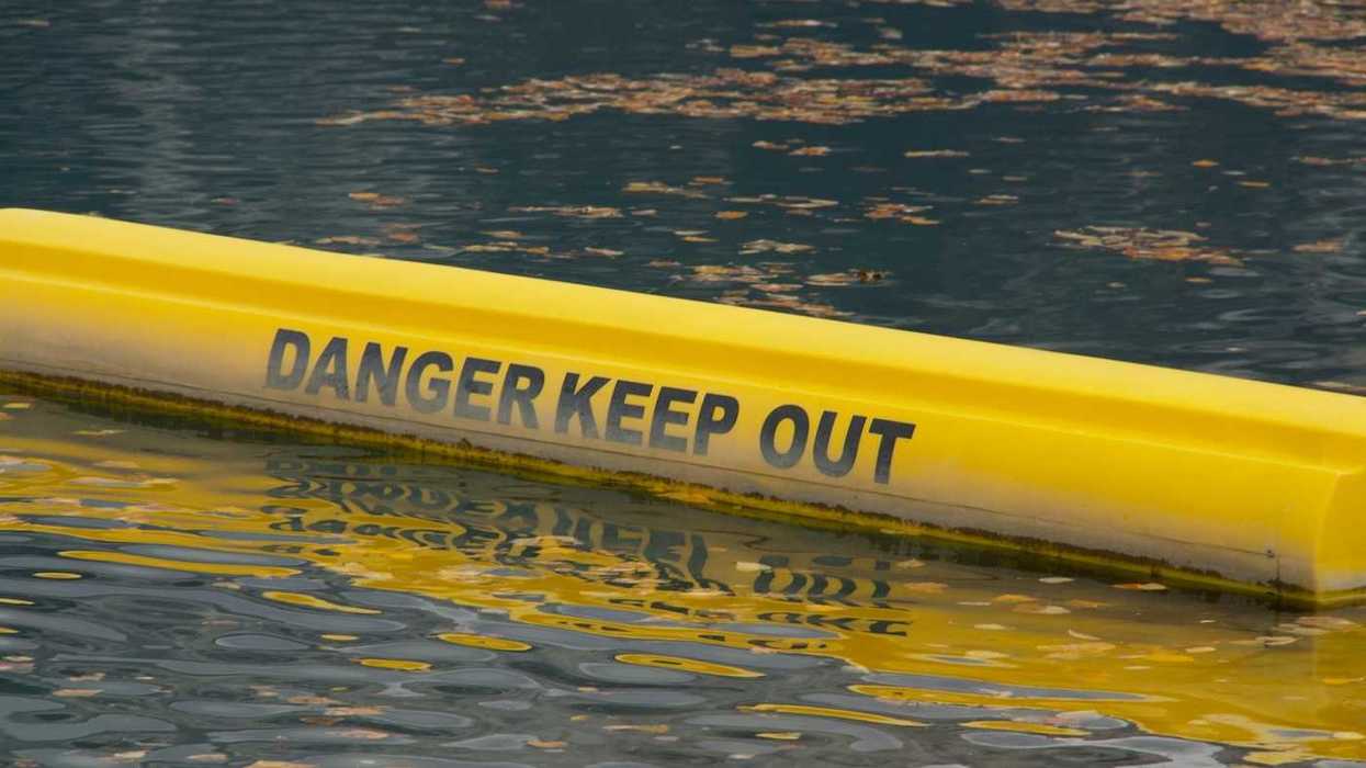 Yellow floating water barrier reading "DANGER KEEP OUT"