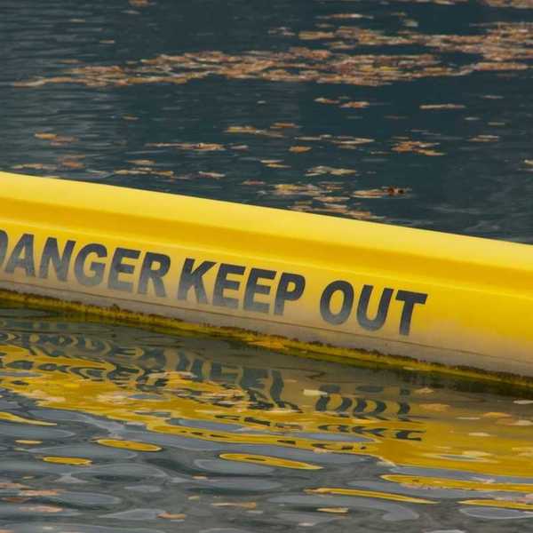 Yellow floating water barrier reading "DANGER KEEP OUT"