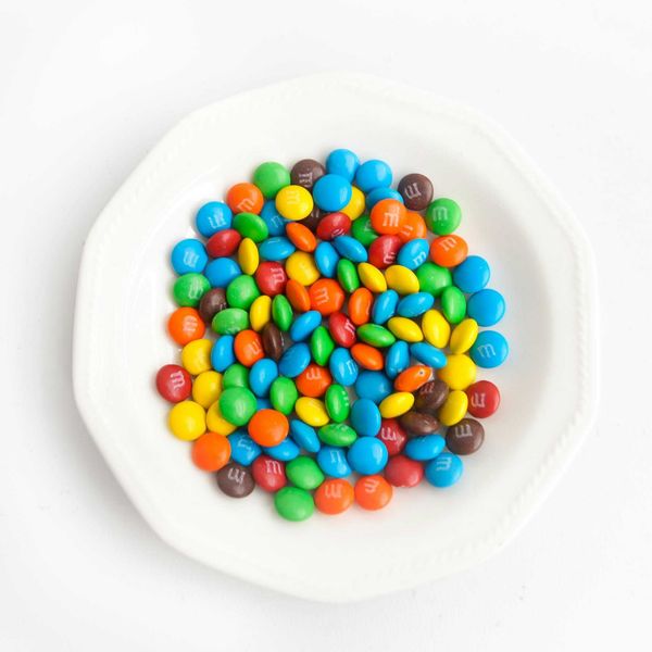 yellow green  blue and red candies on white ceramic round plate.