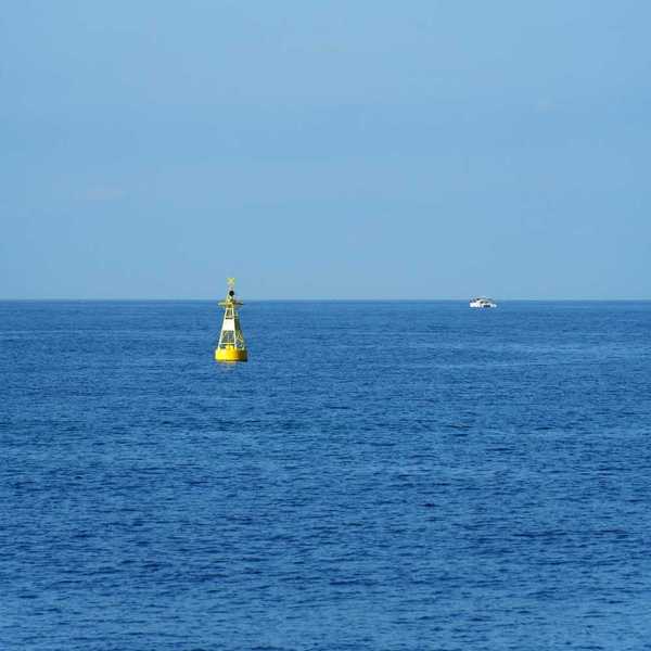 Yellow ocean monitoring buoy with an unidentified white boat nearby