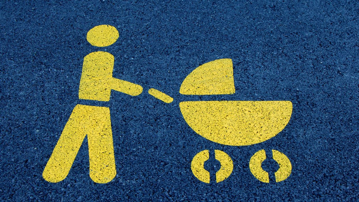 Yellow paint stencil depicting a person pushing a baby carriage on blue surface