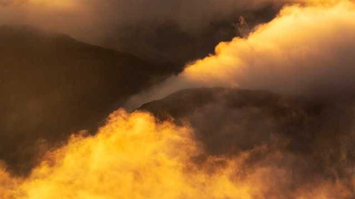 Yellow smoke billowing out of valleys in between mountains