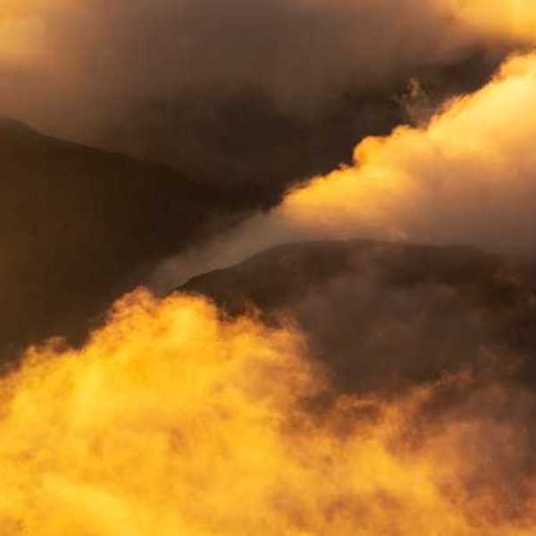 Yellow smoke billowing out of valleys in between mountains