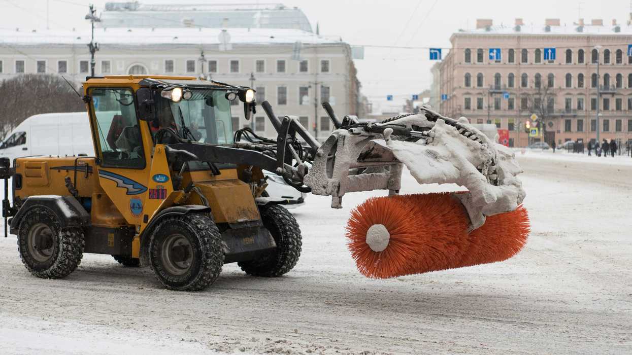 Yellow snow clearer with red roller brush on a street during daytime