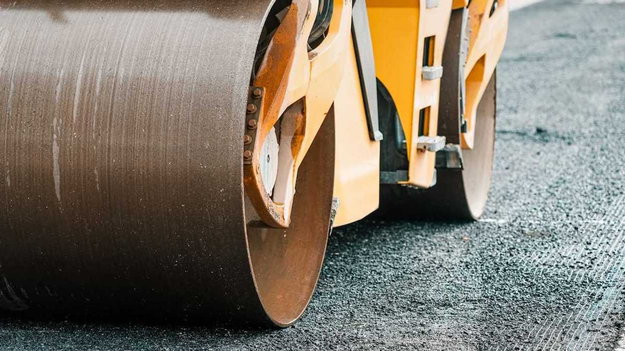 Yellow "Steam roller" compressing fresh asphalt