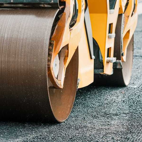 Yellow "Steam roller" compressing fresh asphalt