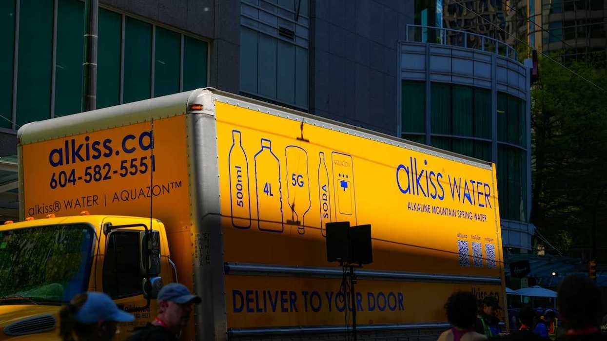 Yellow water delivery truck: "alkiss water. DELIVER TO YOUR DOO"