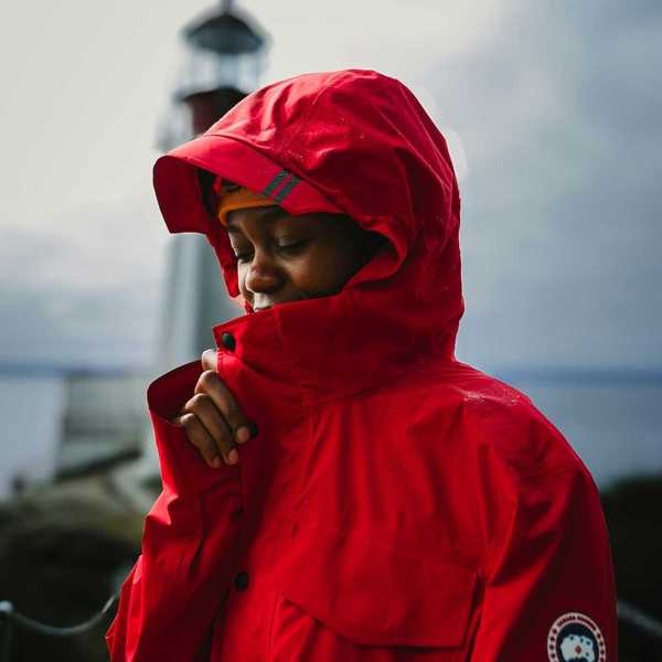 Young brown-skinned boy snuggled into red rain jacket with hood