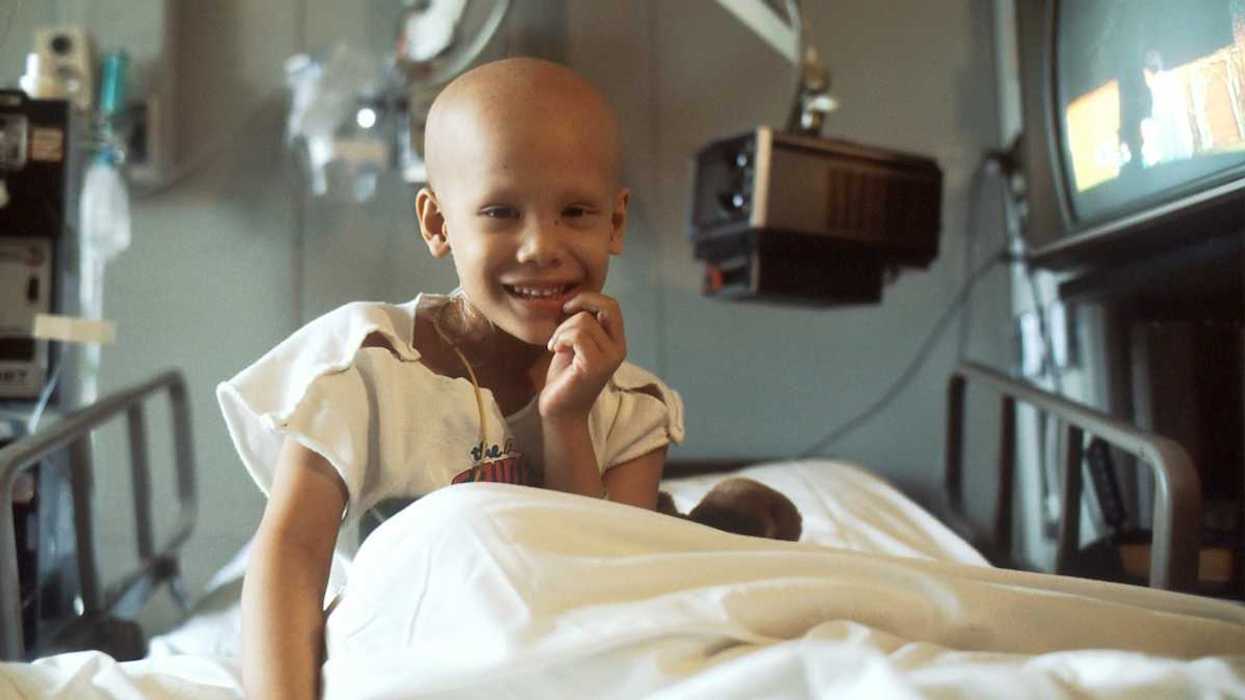 Young Girl sitting up in hospital bed receiving chemotherapy.