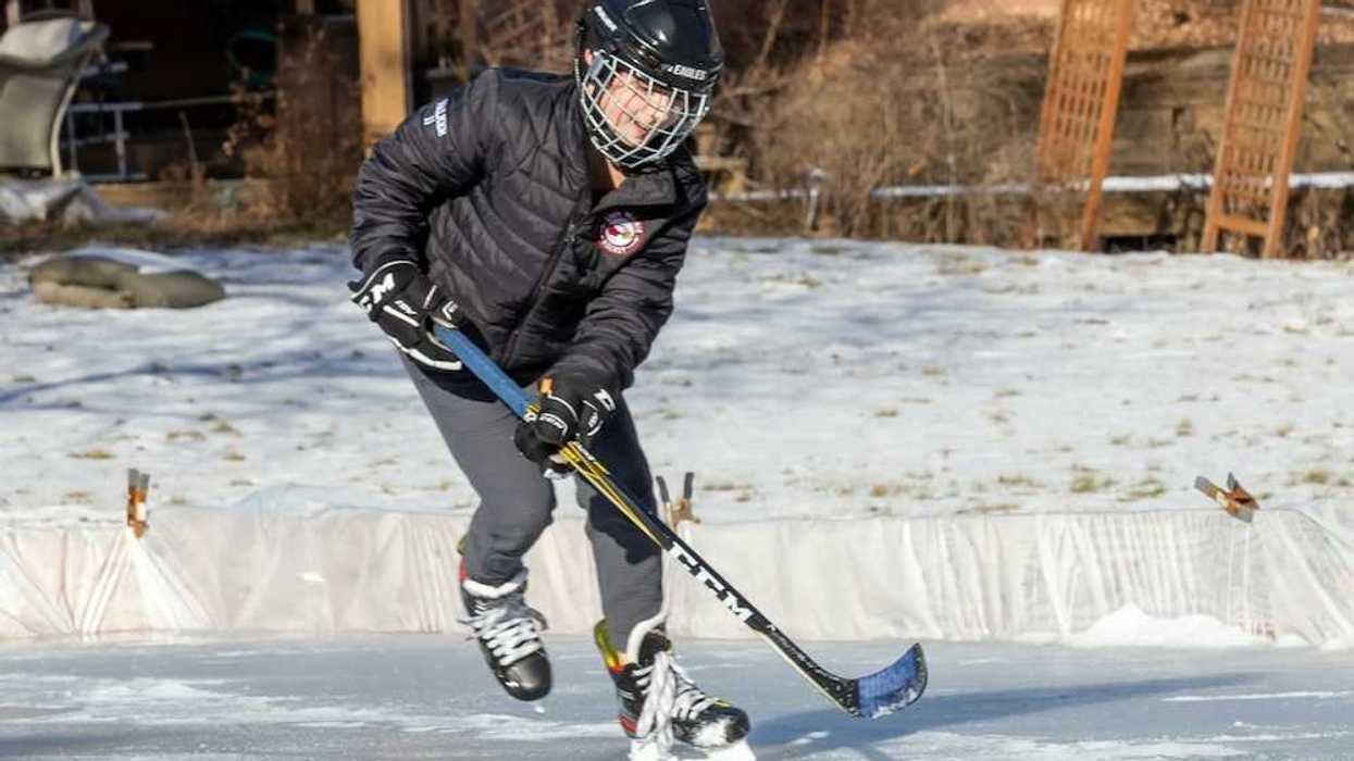 Young person winter-skating on backyard rink with hockey stick and puck