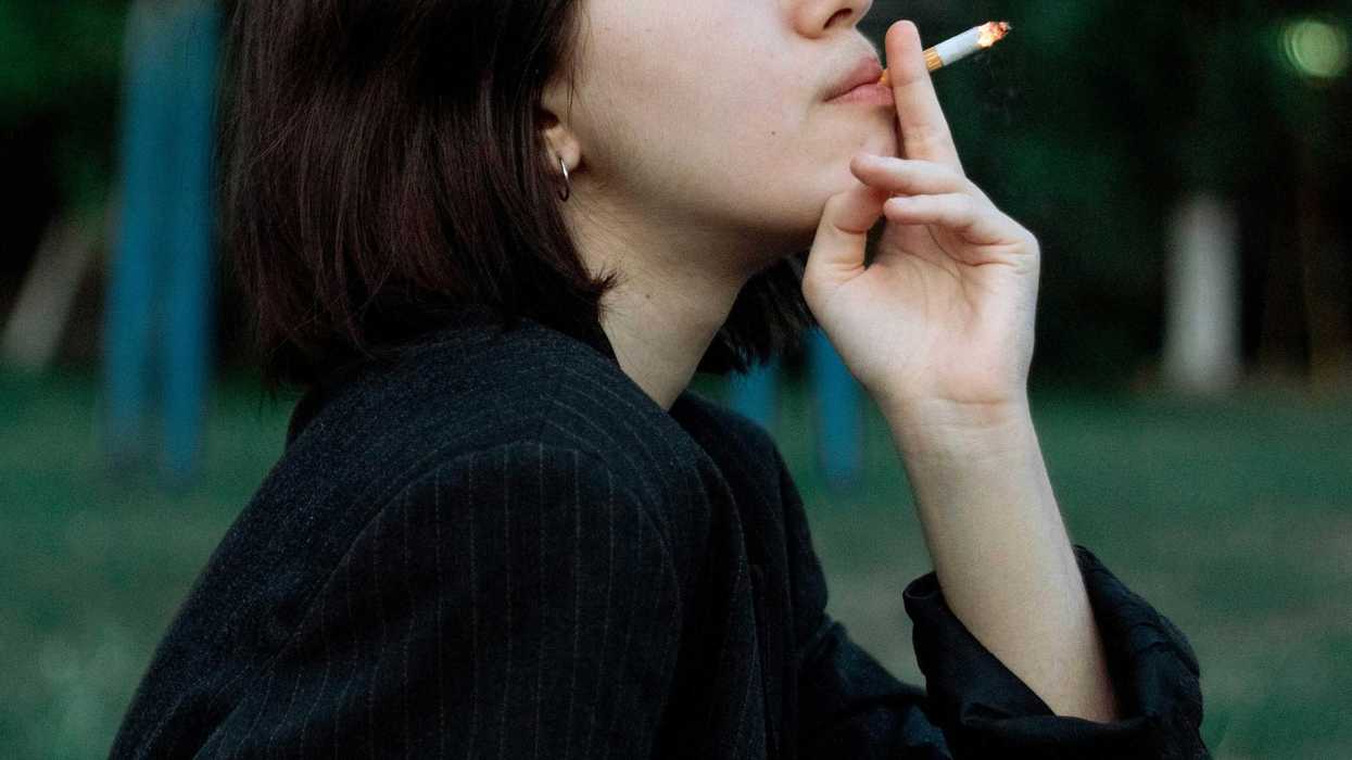 young woman in black long sleeve shirt smoking cigarette.