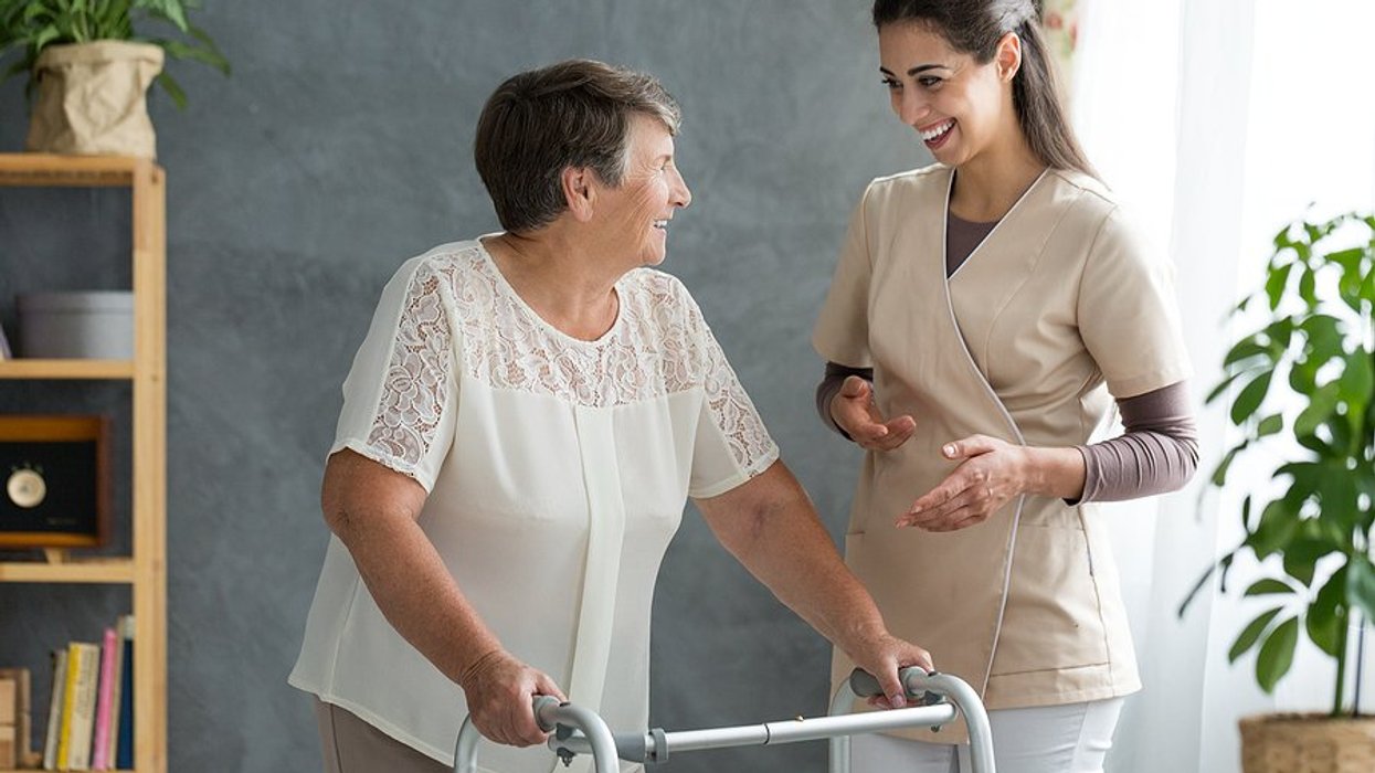 younger woman speaking to senior citizen woman with a walker