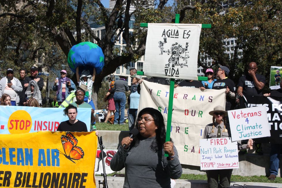 Yvette Arellano, Fenceline Watch, addresses the crowd at the press conference while holding a sign in Spanish that reads, 'Water is life.'